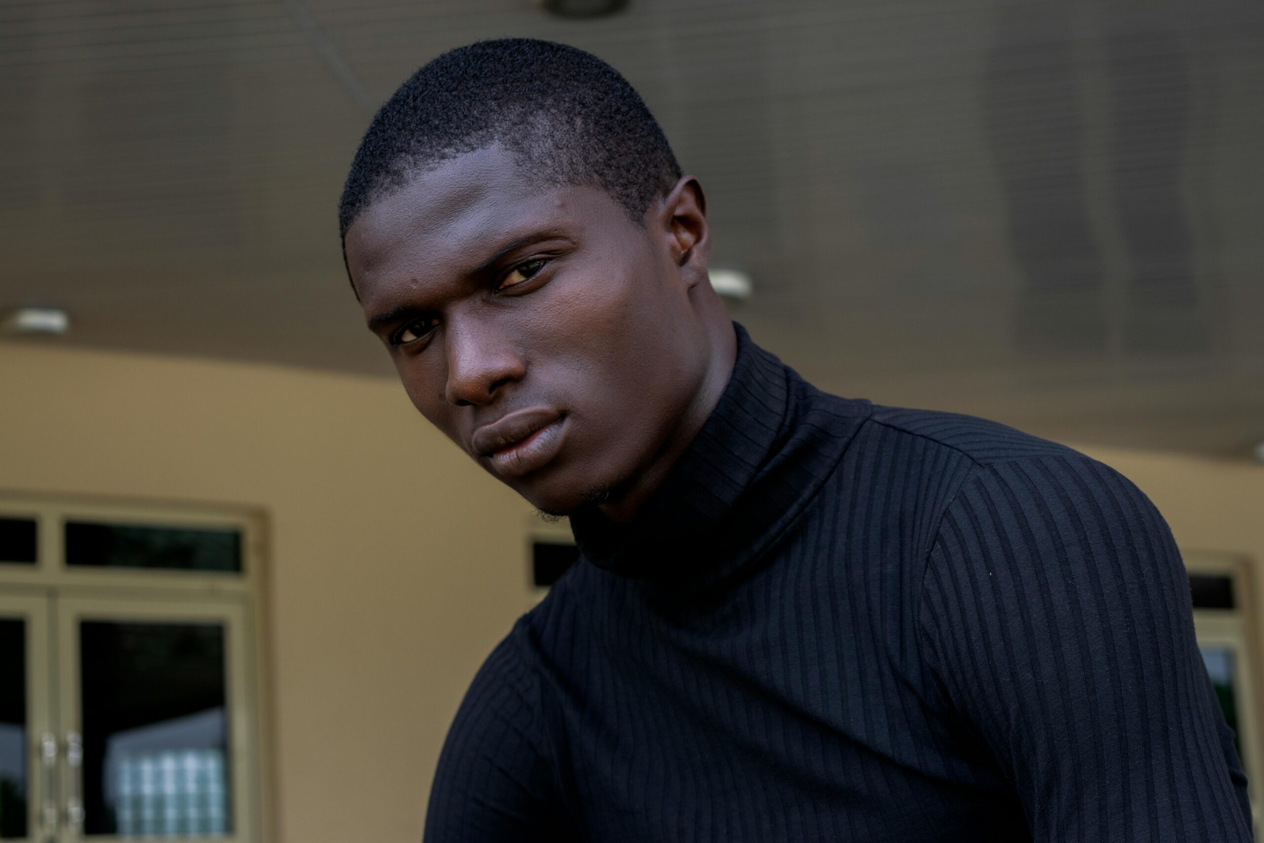 Home A focused portrait of a man indoors wearing a black sweater in Nigeria.